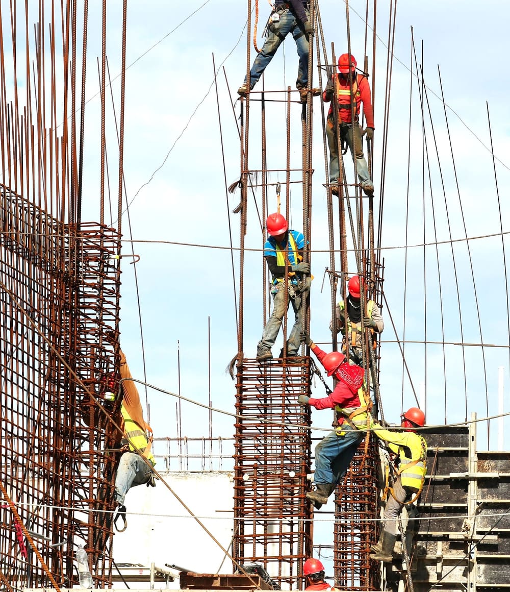 Operai con il casco al lavoro sui ferri d'armatura di un pilastro