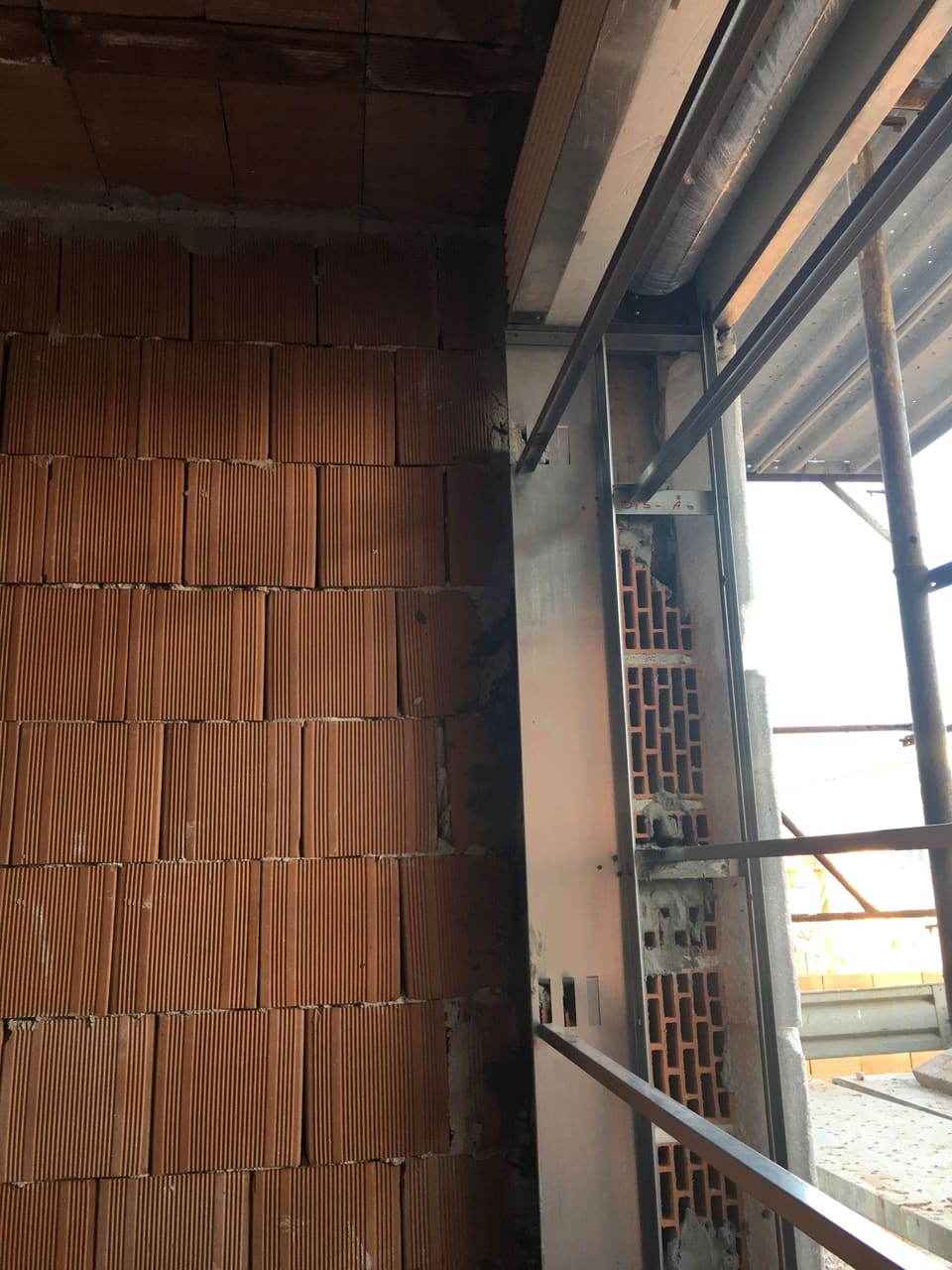 Parete in blocchi di laterizio accanto a un'apertura con ponteggio